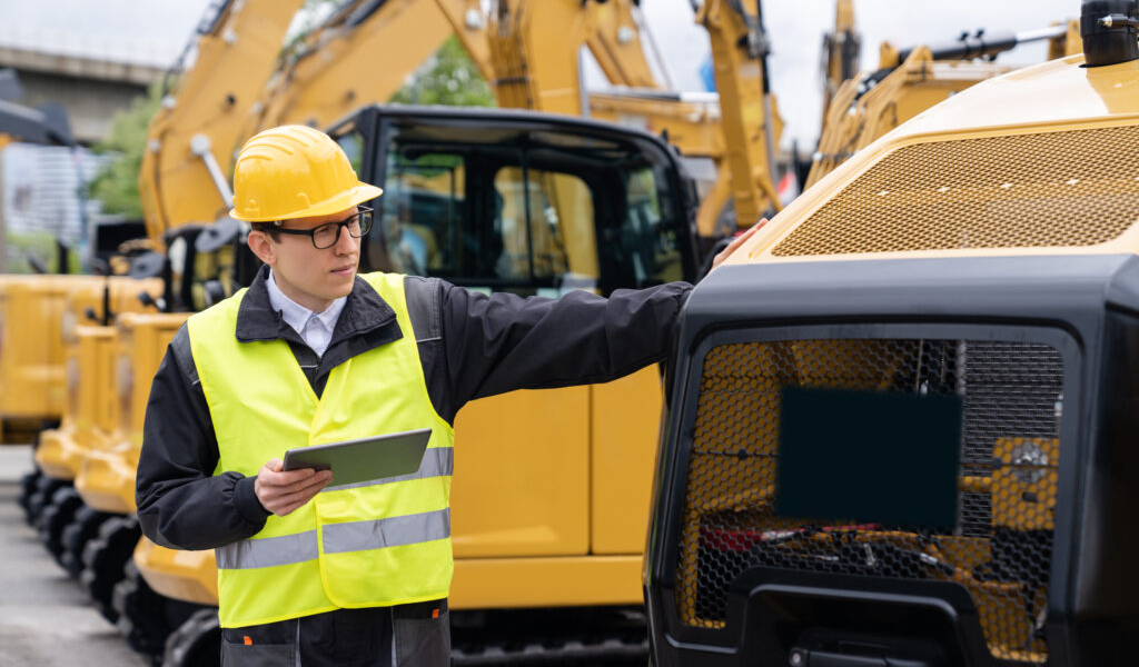 inspector with tablet looking at construction machine