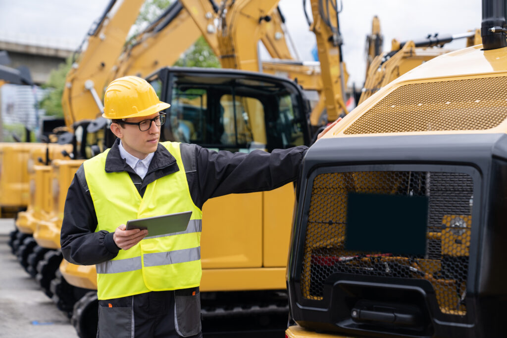 inspector with tablet looking at construction machine