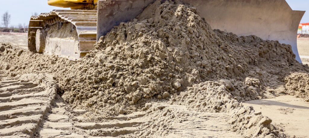 Close up of an earthmoving bulldozer track and blade pushing dirt.