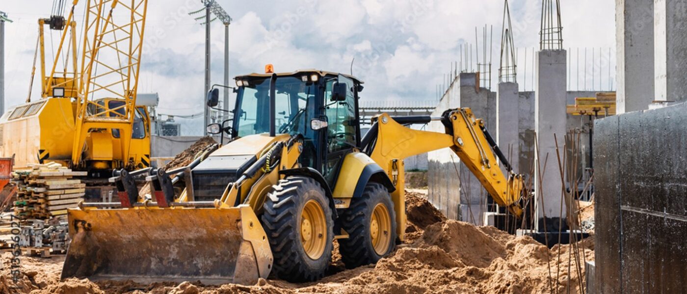 Wheel loader and crawler crane working in an urban construction site.